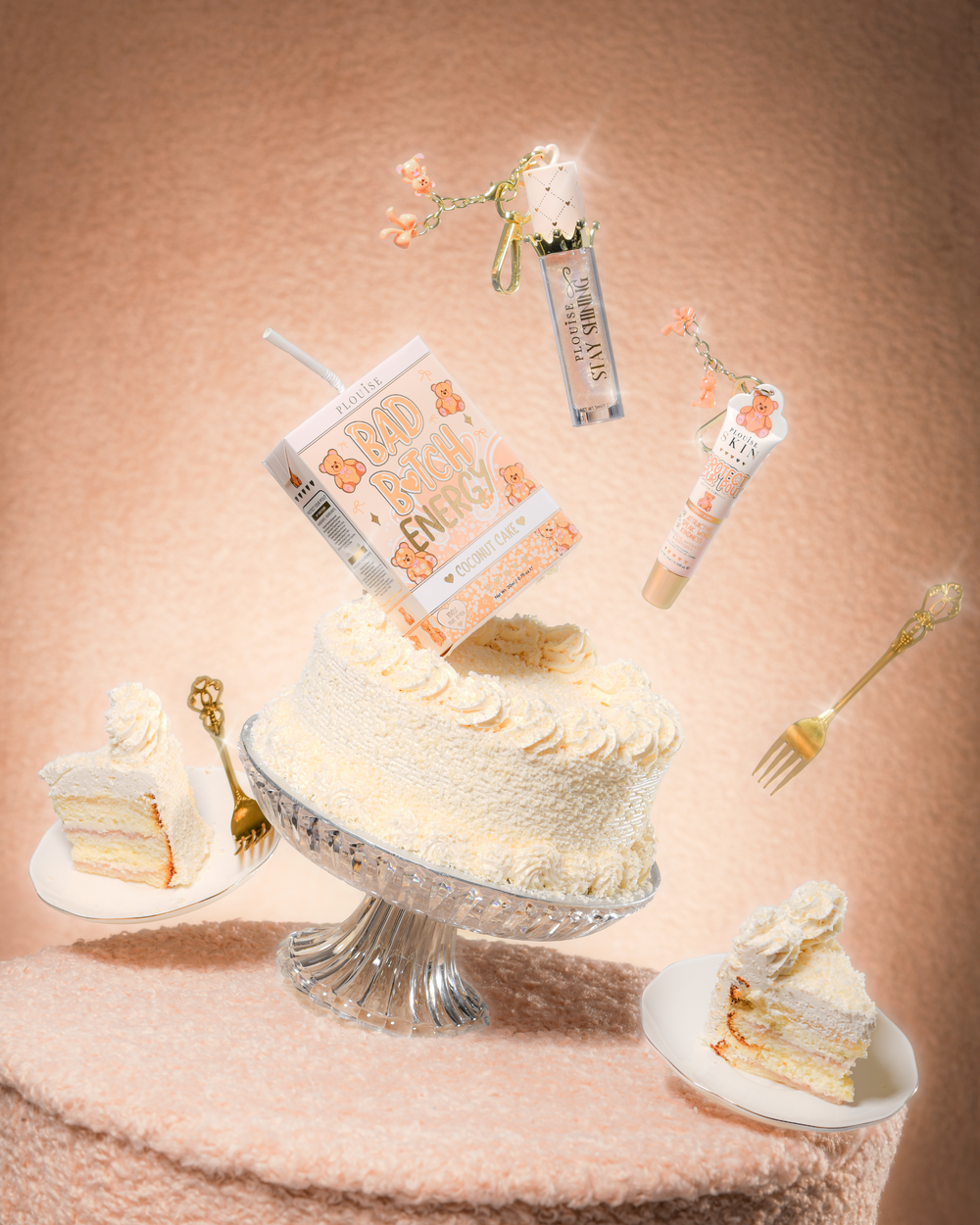 Torta egy mackós szövetasztalon P.Louise Teddy Glitter Bad Bitch Energy Lip Duo-val kókuszos tortában, amely ajakkondicionálót és a torta körül úszó ajakolajat tartalmaz