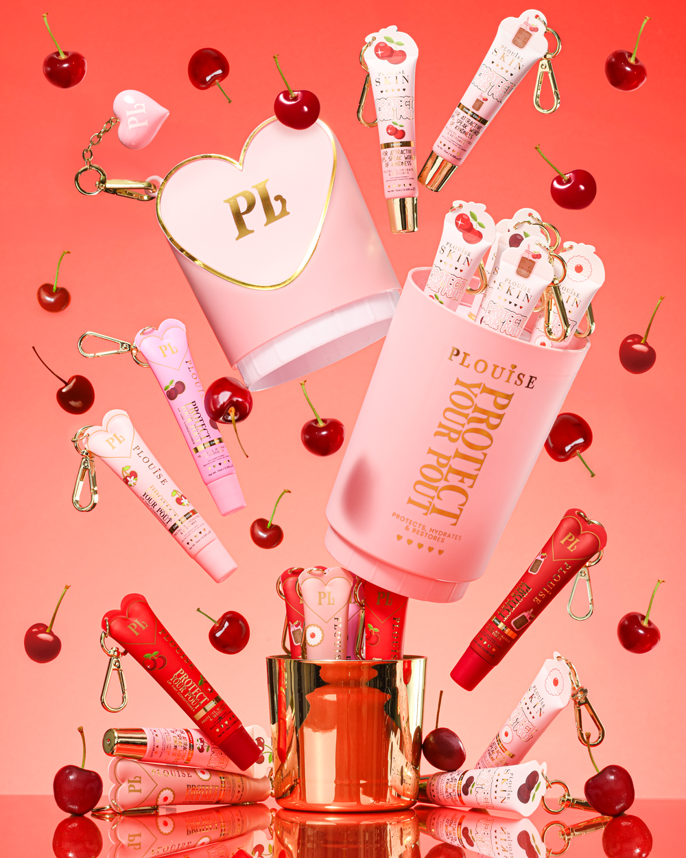 Pink XL Protect Your Pout ajándék szett, amelyet meggy, valamint rózsaszín és piros ajakkondicionálók vesznek körül rózsaszín alapon.