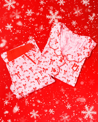 Rózsaszín és fehér csíkos pizsama piros, ünnepi masni mintával, piros háttéren hópelyhekkel