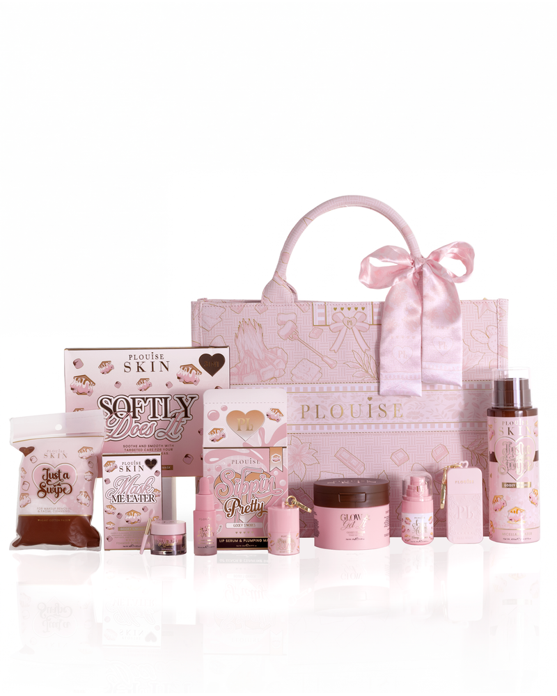A pink boo basket collection from the brand Plouise, featuring a large patterned tote bag with a satin bow and various other pink skincare and fragrance products arranged on a reflective white surface.