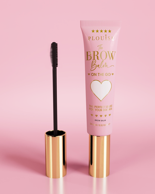 P.Louise Fluffy Soap Brow Balm Instant Fix termék rózsaszín, arany kupakkal ellátott tubusban, fekete szemöldökkefével, rózsaszín háttér előtt megjelenítve.