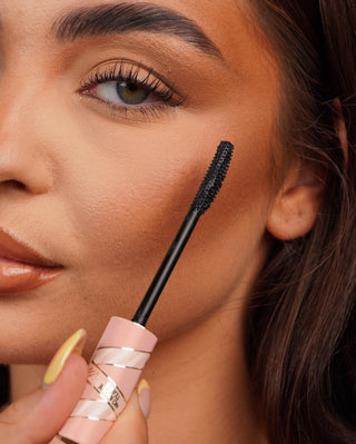 Közeli kép egy P. Louise könnyálló szempillaspirál pálcájáról egy személy szeméhez közel, elmosódott háttérrel