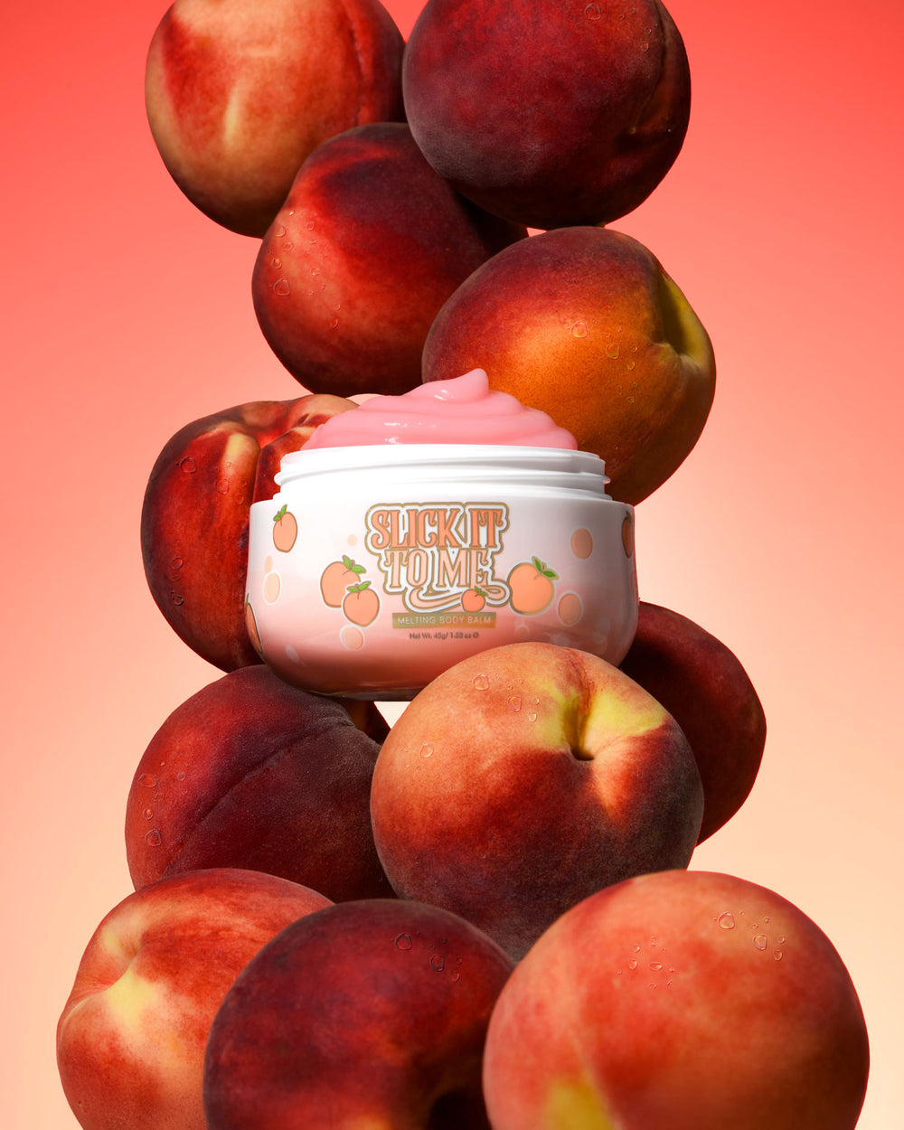 Jar of P. Louise Slick It To Me Peach Melting testbalzsam rózsaszín krémmel, barackokkal körülvéve gradiens alapon