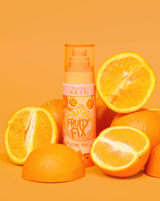 Egy narancssárga üveg P. Louise Fruity Fix Vitamin C Setting Spray narancssárga háttérrel, friss narancsszeletekkel körülvéve.