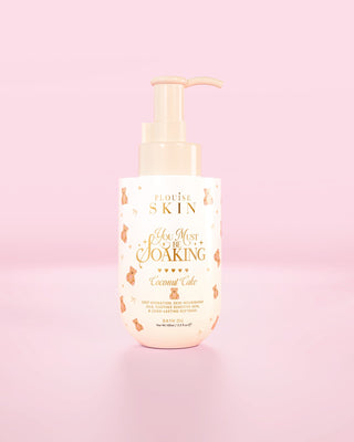 Üveg a P.Louise You Must Be fürdőolaj kókuszos süteményben áztatása rózsaszín háttér előtt